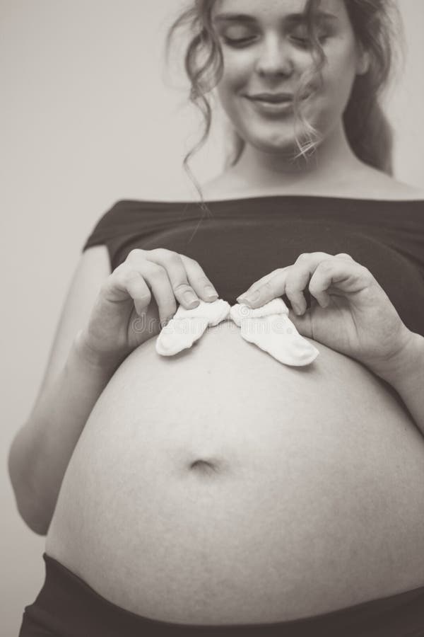 Touching Photo of Pregnancy Moments Young Expectant Mother with Socks on  Her Belly Stock Photo - Image of home, baby: 235027590