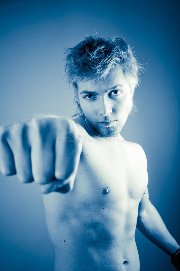 21 year old shirtless man throwing a punch with his right hand toward the c...