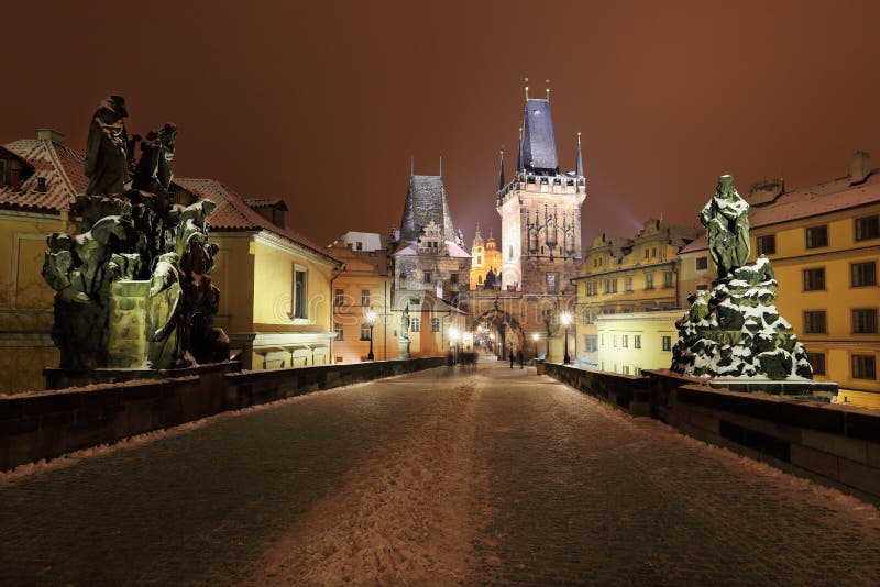 Tour neigeuse colorée de pont de Prague de nuit avec des sculptures de Charles Bridge photographie stock libre de droits Tour neigeuse colorée de pont de Prague de nuit avec des sculptures de Charles Bridge photographie stock libre de droits