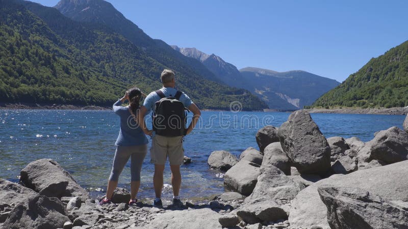 Tourist couple close to the lake in Spanish Pyrenees Mountain in a sunny day