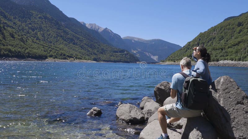 Tourist couple close to the lake in Spanish Pyrenees Mountain in a sunny day