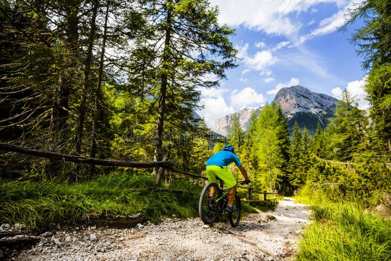 Tourist cycling in Cortina d `Ampezzo, stunning rocky mountains on the background. Man riding MTB enduro flow trail. South Tyrol