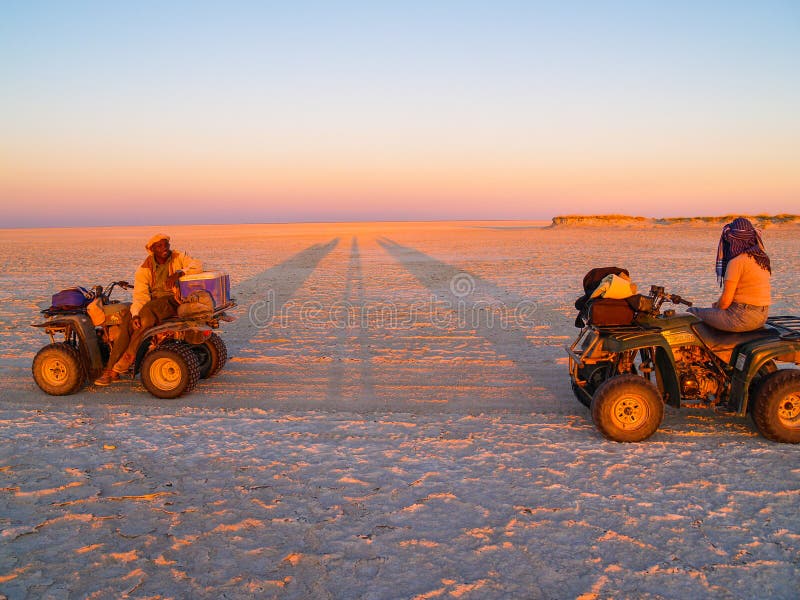Tourist and guide on quad bikes stop while crossing Makgadikgadi Pans National Park, scenic large flat area of salt pan desert t stock photos Tourist and guide on quad bikes stop while crossing Makgadikgadi Pans National Park, scenic large flat area of salt pan desert t stock photos
