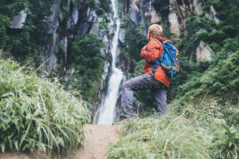 Tourist man with backback rest near the waterfall in rainy fores royalty free stock photo Tourist man with backback rest near the waterfall in rainy fores royalty free stock photo