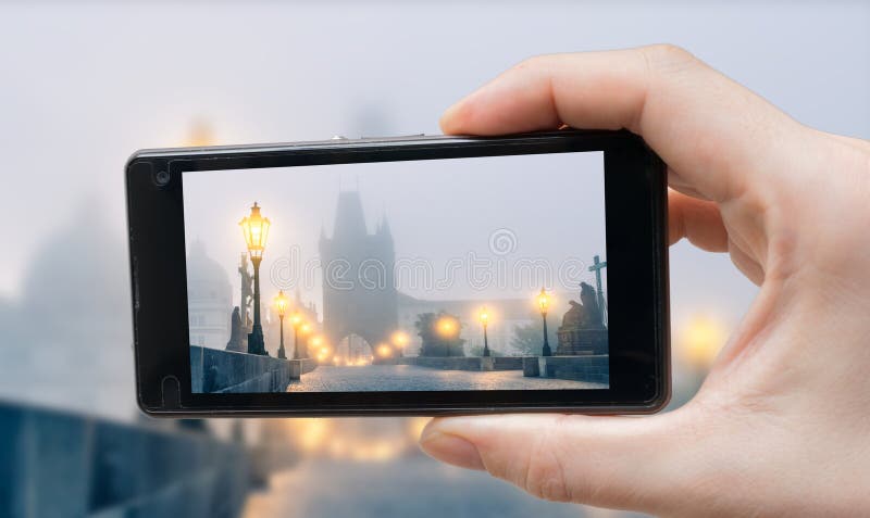 Tourist is photographing Charles Bridge in Prague with smartphone