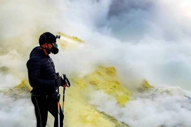 Tourist in protective clothing in the crater of a volcano. Sulfur clouds, volcanic blue lake and pink sunrise. A dangerous journey stock photography Tourist in protective clothing in the crater of a volcano. Sulfur clouds, volcanic blue lake and pink sunrise. A dangerous journey stock photography
