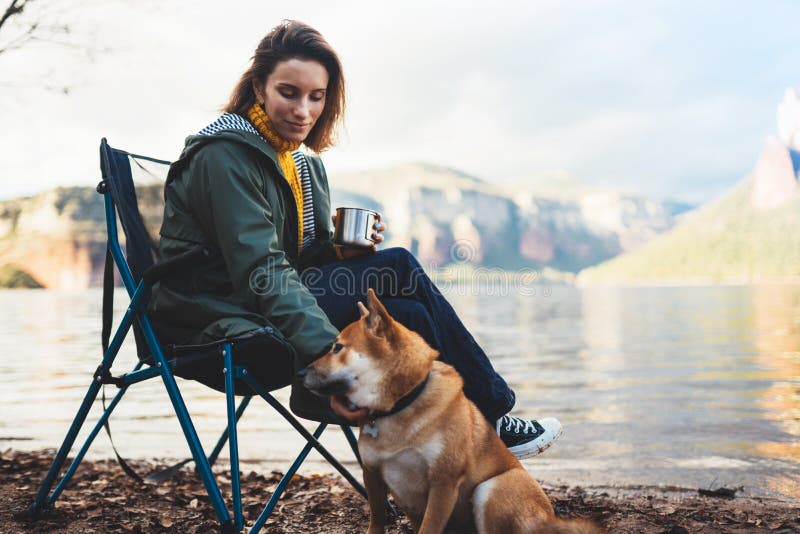 Tourist traveler drink tea girl relax together dog on mountain landscape,  woman hug pet rest on lake shore nature trip