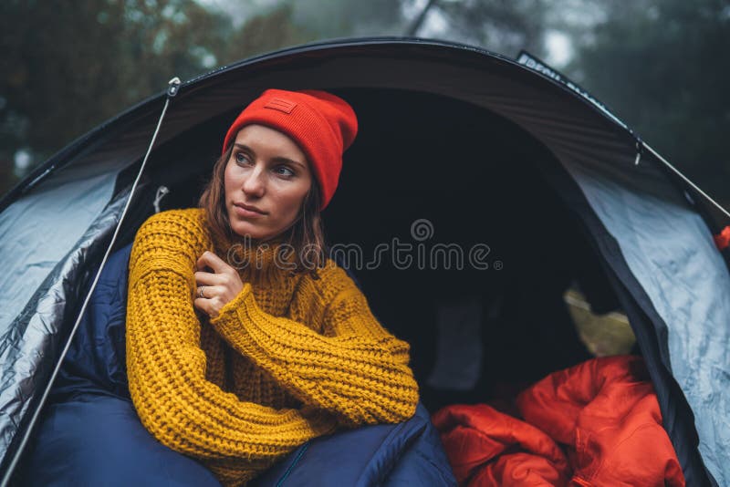 Tourist traveler ralaxing in camp tent in froggy rain forest, hiker woman enjoy mist nature trip, green trekking tourism, rest