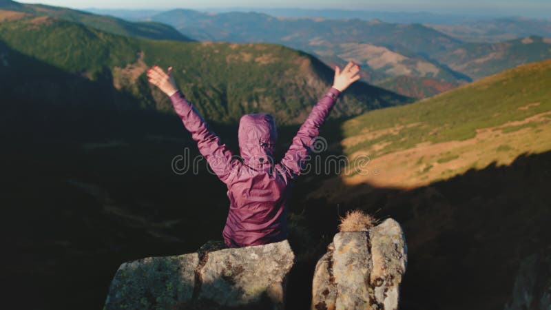 Touriste agitant les mains assis sur le sommet de la montagne