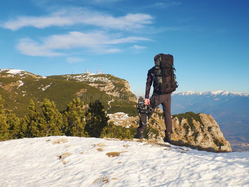 Touriste avec le grand sac à dos et les raquettes se tenant sur le point de vue rocheux et observant dans les montagnes rocheuses image stock Touriste avec le grand sac à dos et les raquettes se tenant sur le point de vue rocheux et observant dans les montagnes rocheuses image stock