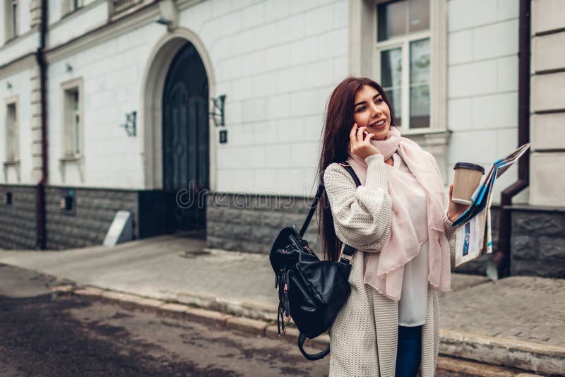 Touriste de jeune femme recherchant la bonne manière employant la carte et parlant au téléphone Fille perdue dans la ville image stock Touriste de jeune femme recherchant la bonne manière employant la carte et parlant au téléphone Fille perdue dans la ville image stock