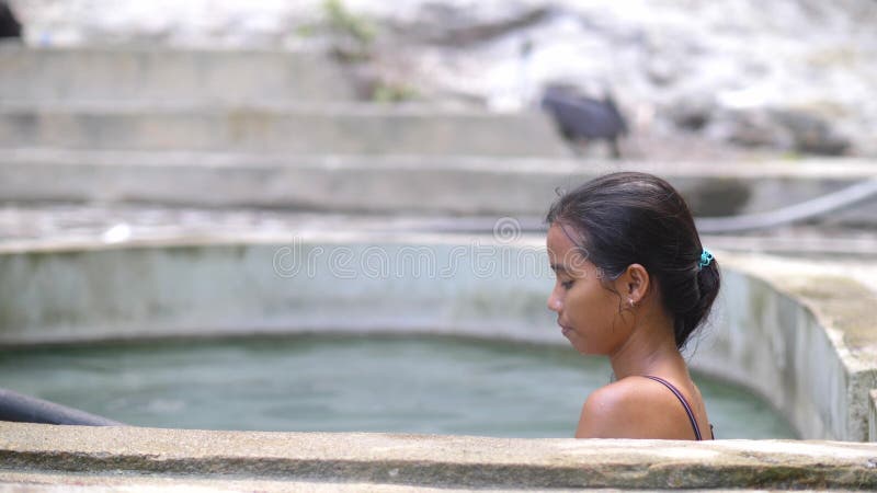 Touriste féminin en profitant de l'eau chaude en source chaude tout en observant la vue de natures. banque de vidéos