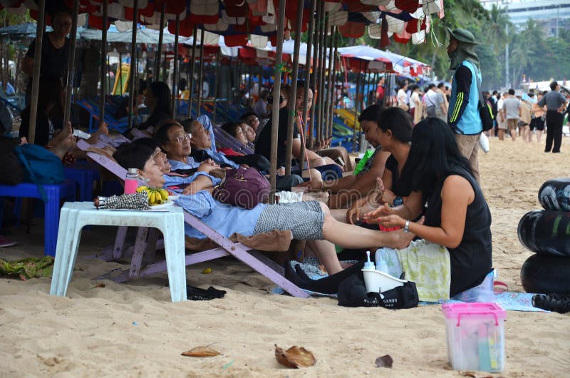 Touristen empfangen eine Massage auf Pataya-Strand von den thailändischen Frauen lizenzfreies stockbild Touristen empfangen eine Massage auf Pataya-Strand von den thailändischen Frauen lizenzfreies stockbild