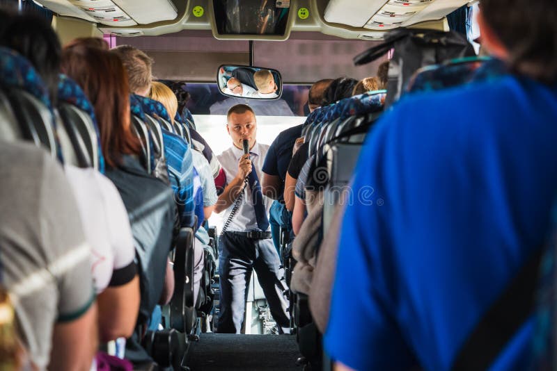 Touristen und ein männlicher Reiseführer mit einem Mikrofon im Bus