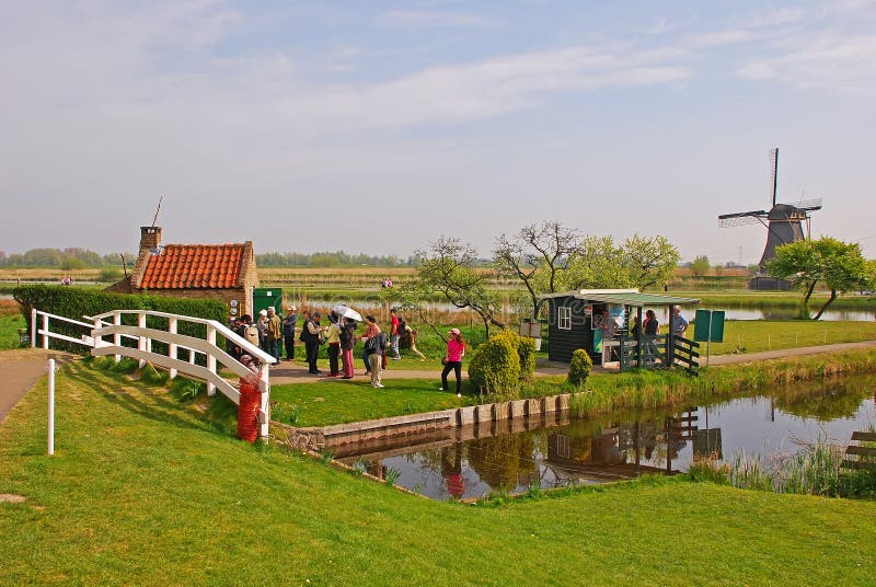Touristen, welche die berühmte Windmühle bei Kinderdijk, die Niederlande besuchen lizenzfreies stockbild Touristen, welche die berühmte Windmühle bei Kinderdijk, die Niederlande besuchen lizenzfreies stockbild