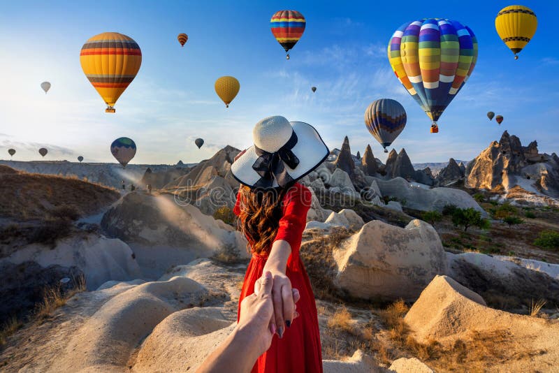 Touristes de femmes tenant la main de l'homme et le menant à des ballons à air festif de Cappadoce, Turquie