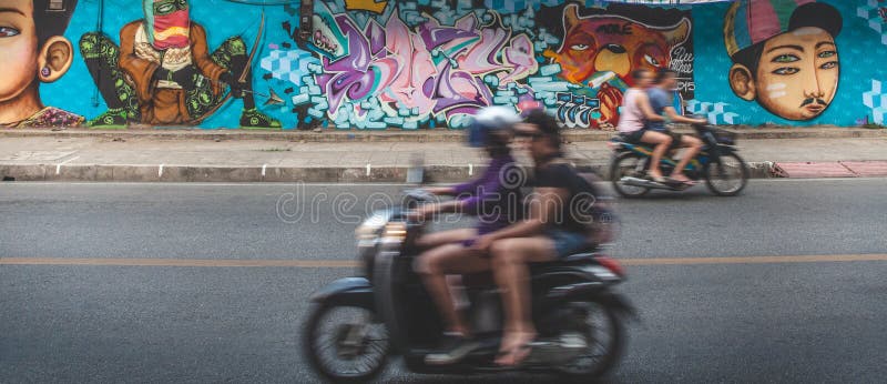 Touristes de la Thaïlande sur le scooter contre le mur de graffiti photo stock Touristes de la Thaïlande sur le scooter contre le mur de graffiti photo stock
