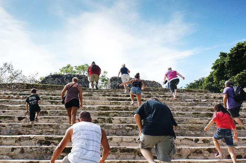 Touristes montant les escaliers des ruines maya