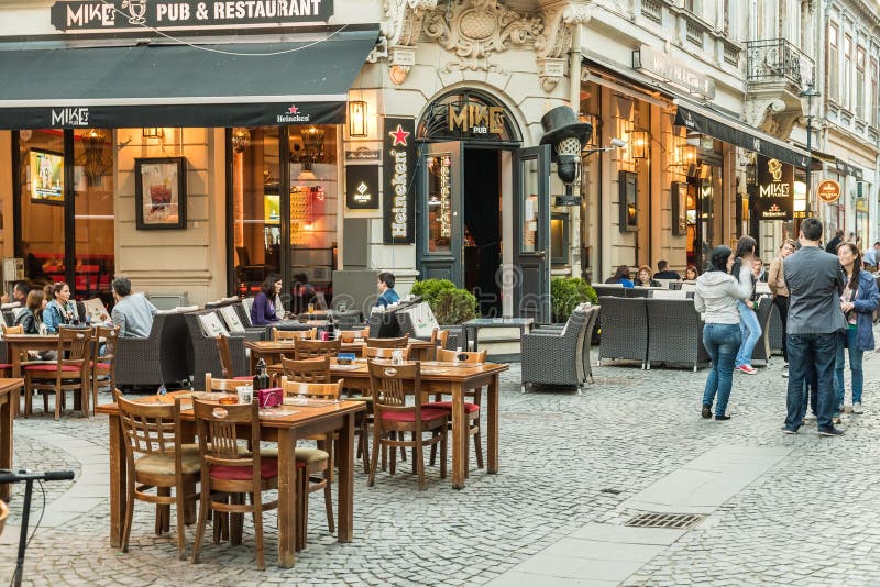 Touristes visitant et prenant le déjeuner au centre ville extérieur de café de restaurant à Bucarest photo stock Touristes visitant et prenant le déjeuner au centre ville extérieur de café de restaurant à Bucarest photo stock