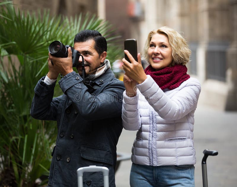 Senior american tourists sightseeing and making photo on camera and smartphone. Senior american tourists sightseeing and making photo on camera and smartphone