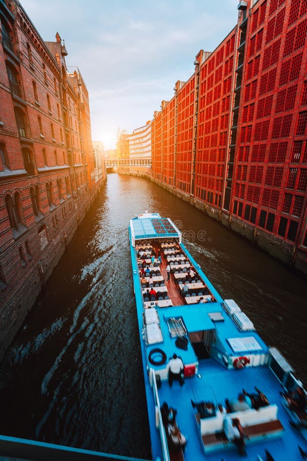 Touristic шлюпка круиза в узком канале известного района склада Speicherstadt с красными кирпичными зданиями в Гамбурге