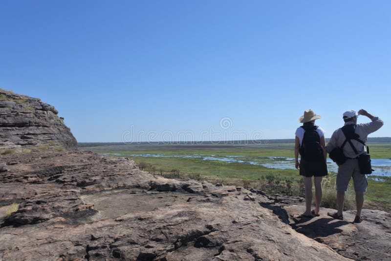 Touristische Paare, die am Ubirr-Felsen-Kunststandort im Nationalpark-Nordterritorium Kakadu von Australien wandern stockbilder Touristische Paare, die am Ubirr-Felsen-Kunststandort im Nationalpark-Nordterritorium Kakadu von Australien wandern stockbilder