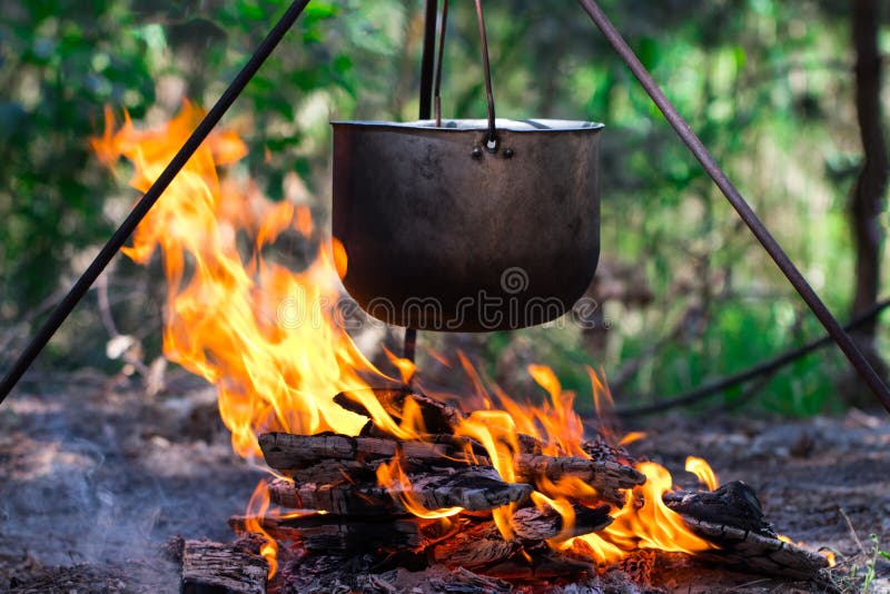 Touristischer Topf, der über dem Feuer auf einem Stativ hängt Kochen im Ca lizenzfreie stockfotos Touristischer Topf, der über dem Feuer auf einem Stativ hängt Kochen im Ca lizenzfreie stockfotos