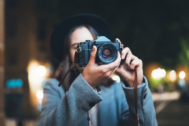 Touristisches Mädchen des Fotografen mit Retro- Kamera Foto auf Hintergrund bokeh Licht im Abendstadt Blogger photoshoot Fotohobby lizenzfreies stockbild