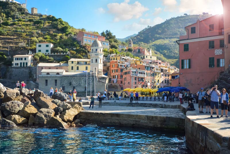 Tourists enjoy the sea, dock and village on a summer morning at the hillside city of Vernazza Italy. Part of the Cinque Terre on the Italian Riviera stock photography Tourists enjoy the sea, dock and village on a summer morning at the hillside city of Vernazza Italy. Part of the Cinque Terre on the Italian Riviera stock photography