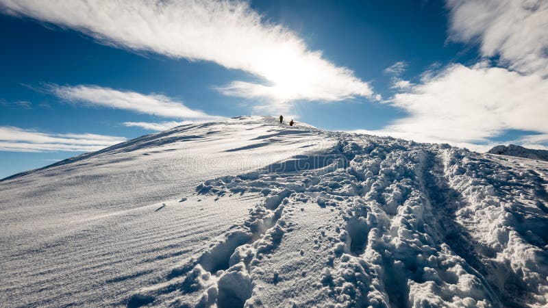 Turisti, ktorí si užívajú vysoké hory v snehu za slnečného dňa