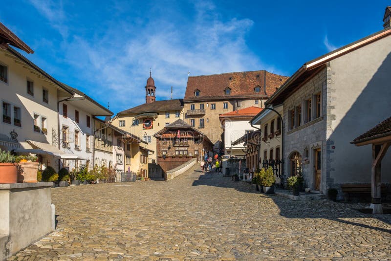 Tourists on the old medieval road in Gruyeres, Switzerland, in autumn light. stock photos Tourists on the old medieval road in Gruyeres, Switzerland, in autumn light. stock photos