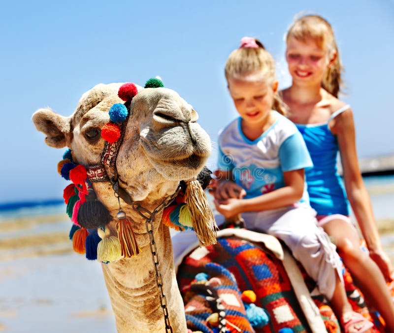 Turisti, bambini a cavallo di cammelli sulla spiaggia di Egitto.