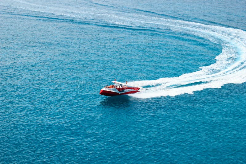 KEMER, TURKEY - MAY 2017: Motor boat with tourists making turn with high speed leaving trail in water. KEMER, TURKEY - MAY 2017: Motor boat with tourists making turn with high speed leaving trail in water