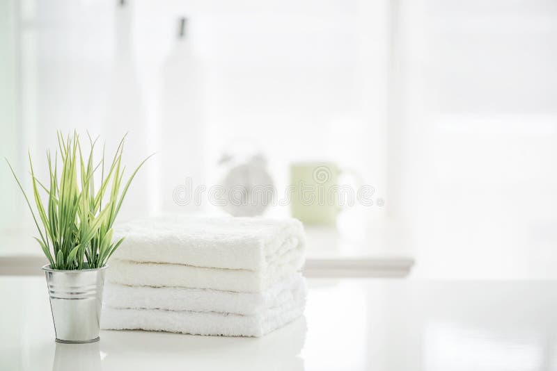 Towels on White Table with Copy Space on Blurred Bathroom Background