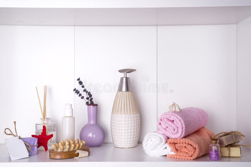 Towels in a wooden tray with aroma chopsticks, candles, seashells, massage washcloths and a bottle with a dispenser