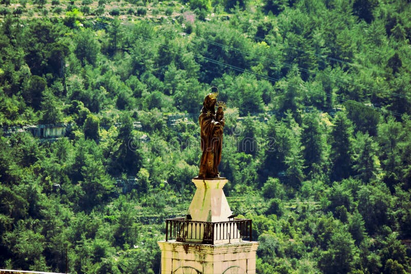 Tower of the Church Saydet El Tallet in the Lebanese village Deir al Qamar with a Virgin Marie statue on top sorrounded by green forest. Tower of the Church Saydet El Tallet in the Lebanese village Deir al Qamar with a Virgin Marie statue on top sorrounded by green forest