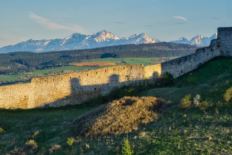 The tower and rock wall fortification around the Spissky hrad castle with High Tatras on horizont