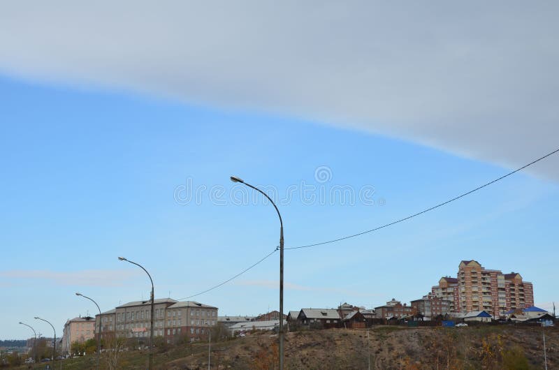 This picture shows town houses on the hill with straight line of clouds. This picture shows town houses on the hill with straight line of clouds