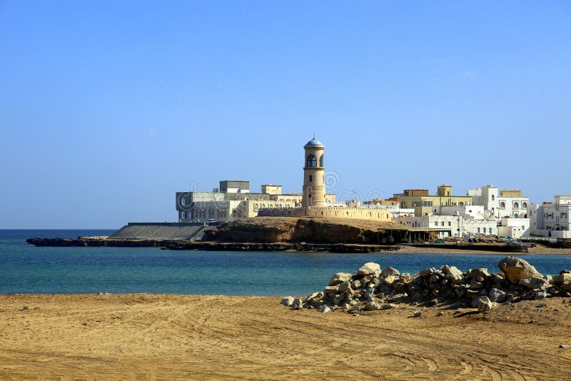 The town of Sur on the sea and the lighthouse of Al Ayjah, at the entrance to the port, both seen from the beach, Oman