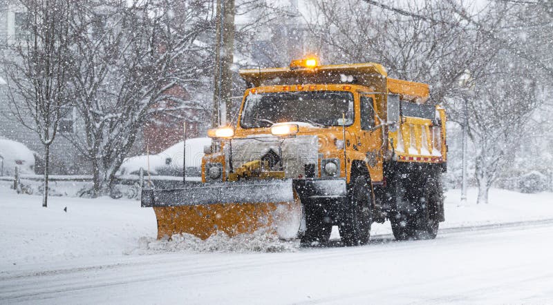 Yellow snowplow clearing a road during a snow storm royalty free stock images