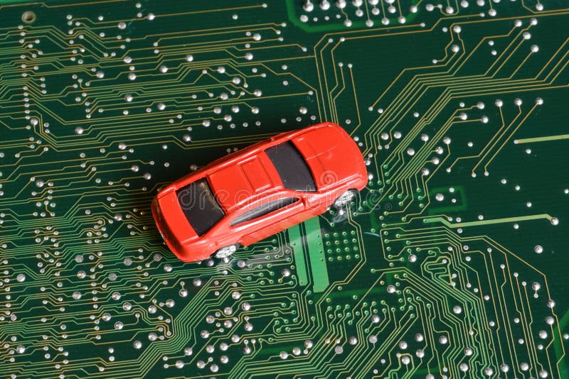 Toy cars on electronic board and microchip. The shortage of microchips and semiconductors creates a shortage of new cars.