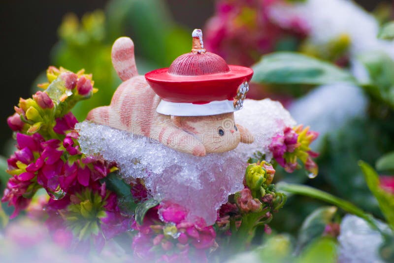 Toy cat lie prone on ice of flowers