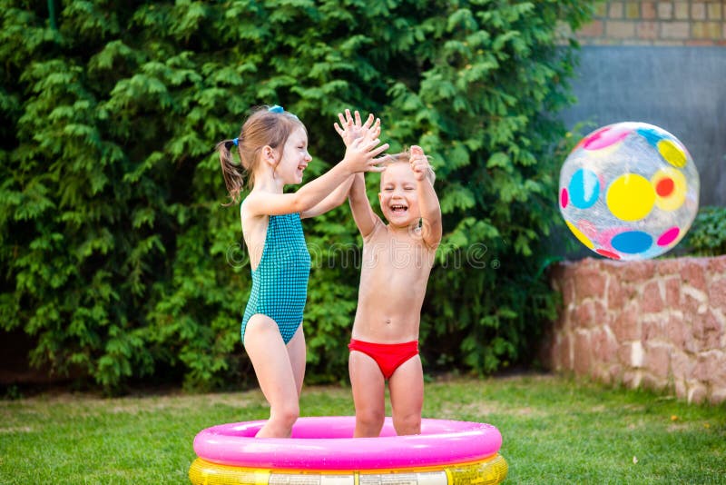 Toy for children games. Children playing with Inflatable rubber beach ball. in water pool. Summer holiday. Boy and Girl Playing in
