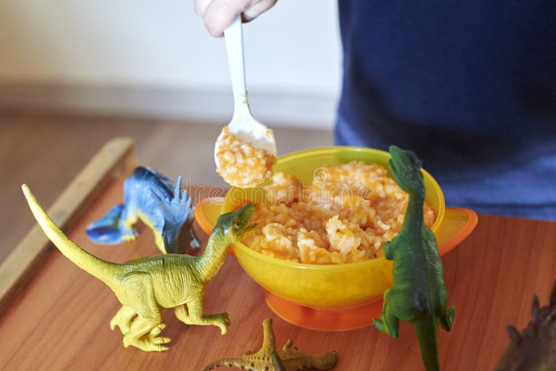 Toy Dinosaurs Stand on a Children`s Table Near a Plate of Porridge ...