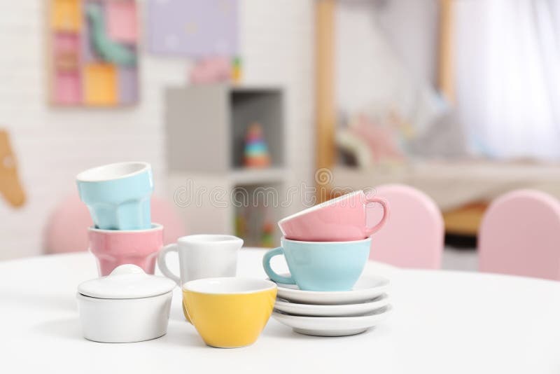 Toy dishware on small table in child`s room, closeup