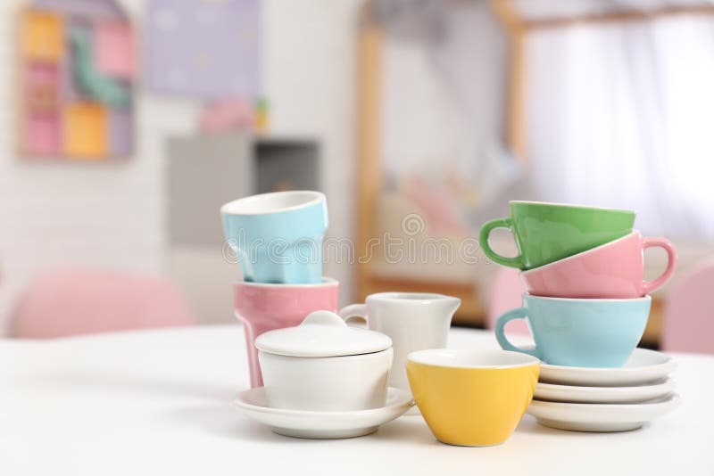 Toy dishware on small table in child`s room, closeup