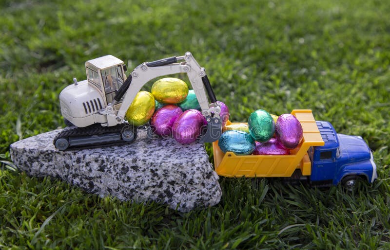 toy excavator and dump truck with colorful chocolate eggs. Easter greetings