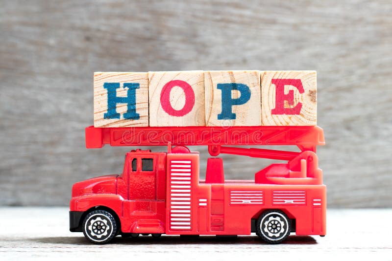 Toy fire ladder truck hold letter block in word hope on wood background