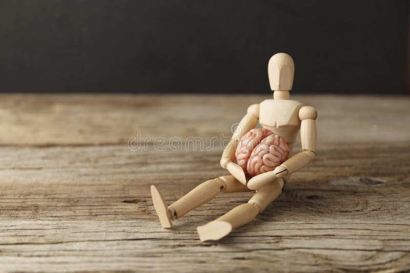 Toy man holds an anatomical brain in his hands. Care and therapy, psychological symptoms. Neuroligic diseases.