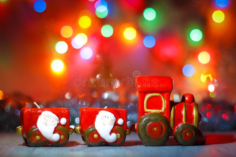 Toy Steam Train med Santa Claus på en bakgrund av guld- girlander och suddighet av kulöra ljus royaltyfria foton Toy Steam Train med Santa Claus på en bakgrund av guld- girlander och suddighet av kulöra ljus royaltyfria foton
